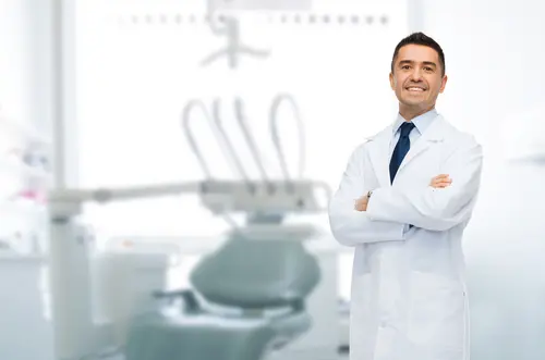 Dentist smiling infront of a dental chair.